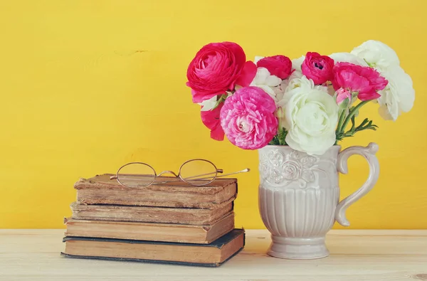 Belo buquê de flores no vaso ao lado de livros antigos — Fotografia de Stock