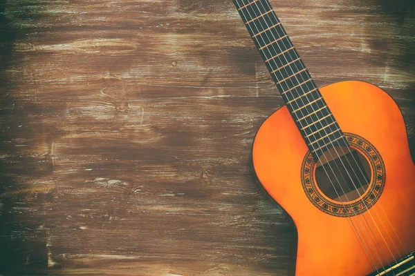 Close up of acoustic guitar against a wooden background — Stock Photo, Image
