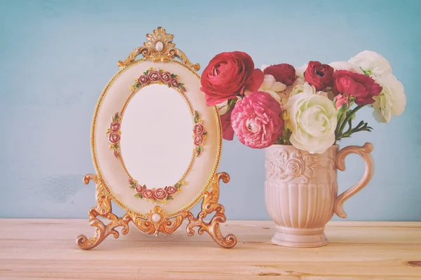 Buquê de flores da primavera ao lado de moldura de foto vintage em branco — Fotografia de Stock