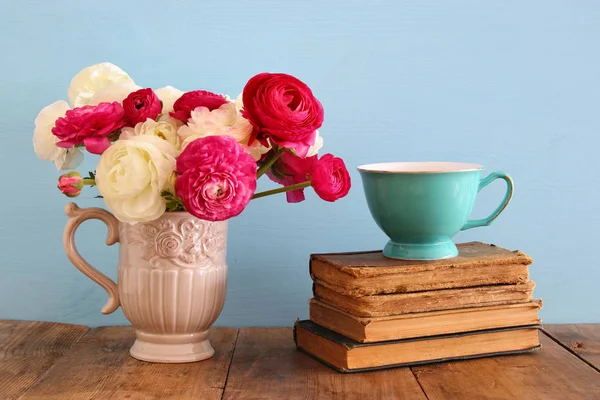 Hermoso ramo de flores de primavera en el jarrón junto a los libros antiguos en la mesa de madera —  Fotos de Stock