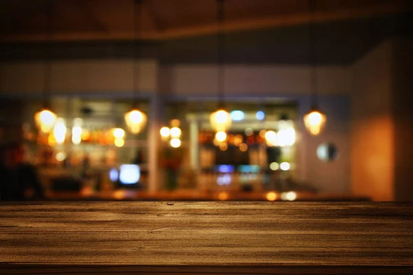 Wooden table in front of abstract blurred restaurant lights — Stock Photo, Image