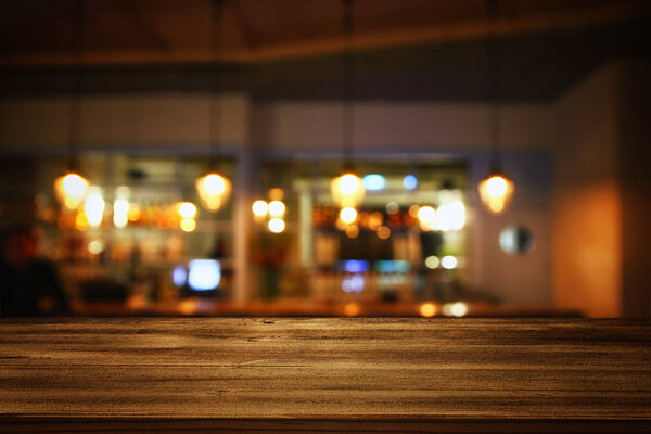 деревянный стол перед абстрактными размытыми огнями ресторана
