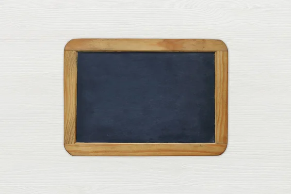Empty vintage blackboard on white wooden background — Stock Photo, Image