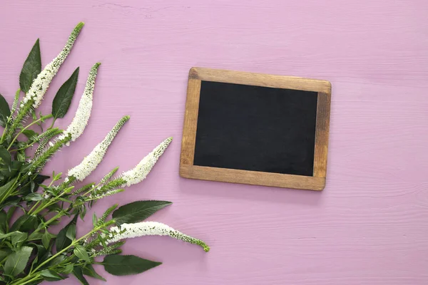 Vita blommor arrangemang och blackboard på trä bakgrund — Stockfoto