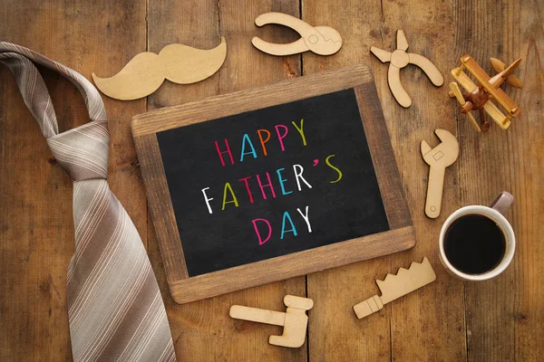 Top view image of fathers day composition with wooden shape tools, necktie , cup of coffee and blackboard — Stock Photo, Image