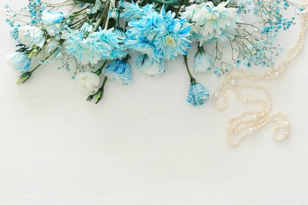 Vista superior do arranjo de flores azuis bonitas e delicadas ao lado do colar de pérolas — Fotografia de Stock
