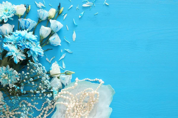 Top view of beautiful and delicate blue flowers arrangement next to pearls necklace — Stock Photo, Image