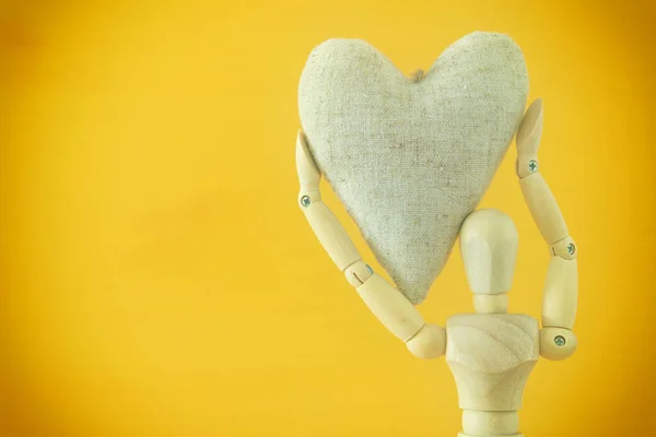 Manequim de madeira segurando um coração. Conceito de amor, relacionamento e afeto — Fotografia de Stock