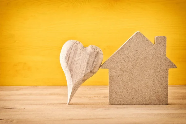 Houten huis model met naast hart op oude tafel — Stockfoto