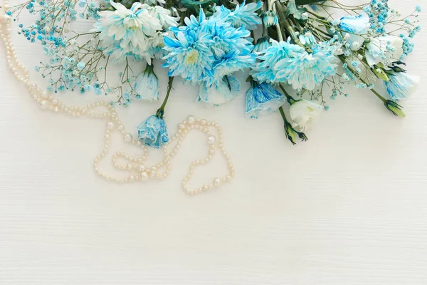 Top view of beautiful and delicate blue flowers arrangement next to pearls necklace — Stock Photo, Image