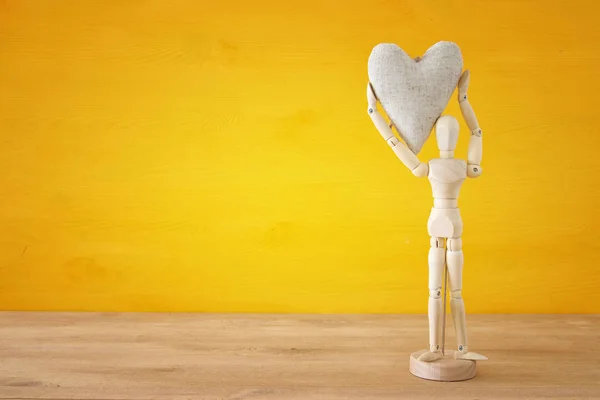 Wooden dummy holding a heart. Love, relationship and affection concept — Stock Photo, Image
