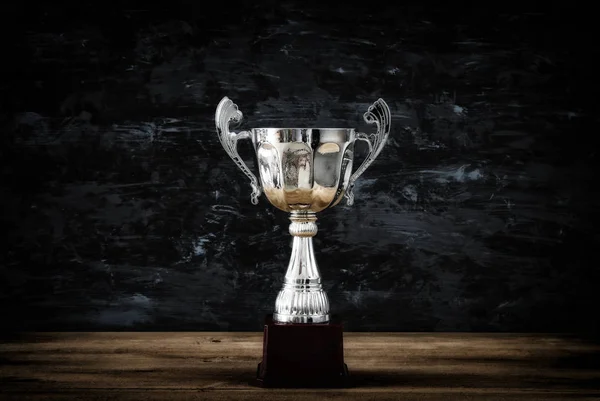 Imagem chave baixa do troféu sobre a mesa de madeira e fundo escuro — Fotografia de Stock