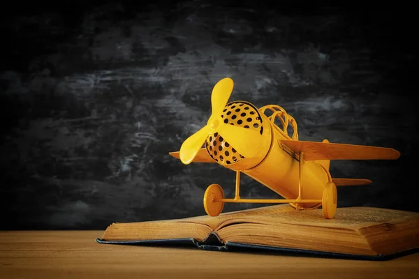 Spielzeugflugzeug und das aufgeschlagene Buch auf Holztisch. — Stockfoto