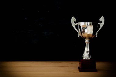 düşük anahtar görüntü Trophy üzerinde ahşap masa ve koyu arka plan