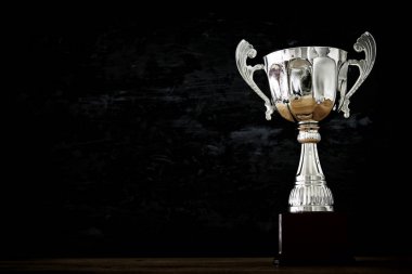 düşük anahtar görüntü Trophy üzerinde ahşap masa ve koyu arka plan
