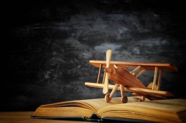 Oyuncak uçak ve ahşap masa üzerinde açık kitap.