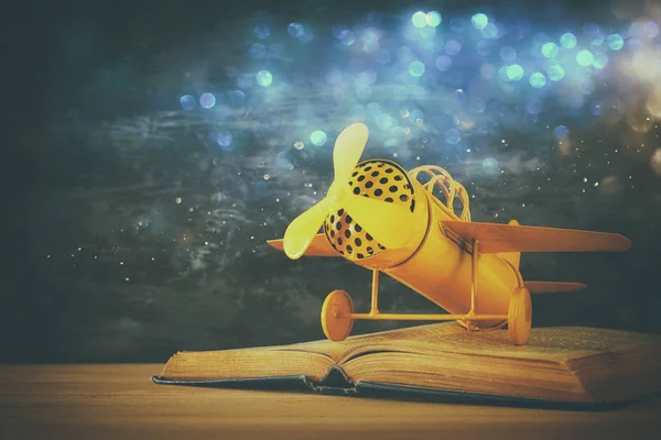 おもちゃの飛行機、木製テーブルの上開く本. — ストック写真