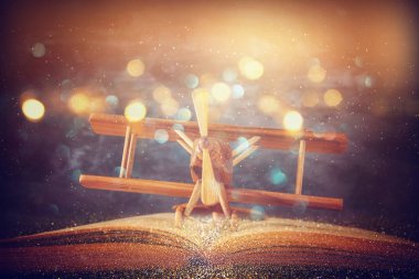 Oyuncak uçak ve parlak ışıklar ile ahşap masa üzerinde açık kitap