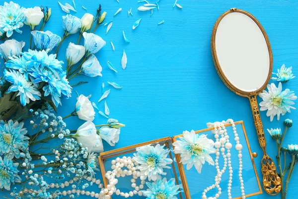 Arranjo de flores azuis bonitas e delicadas ao lado de colar de pérolas e espelho de mão — Fotografia de Stock