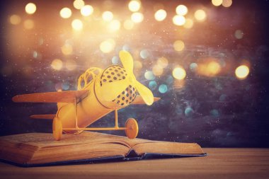 Oyuncak uçak ve ahşap masa üzerinde açık kitap.