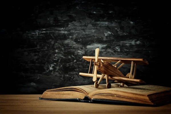 El avión de juguete y el libro abierto sobre la mesa de madera — Foto de Stock