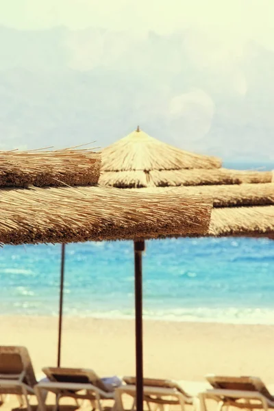 Tropiska hav och strand stolar under paraplyer. Sommar resor och semester koncept — Stockfoto
