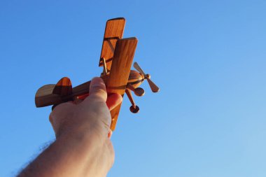 Mavi gökyüzü karşı ahşap oyuncak uçak tutan adamın el yakın çekim