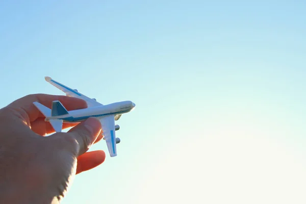 Close up of man's hand holding toy airplane against blue sky — Stock Photo, Image