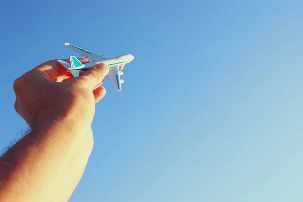 Close up of man's hand holding toy airplane against blue sky — Stock Photo, Image