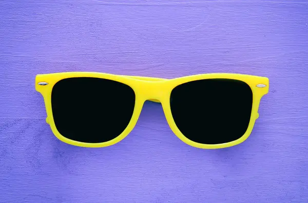 Occhiali da sole giallo hipster su sfondo di legno viola — Foto Stock