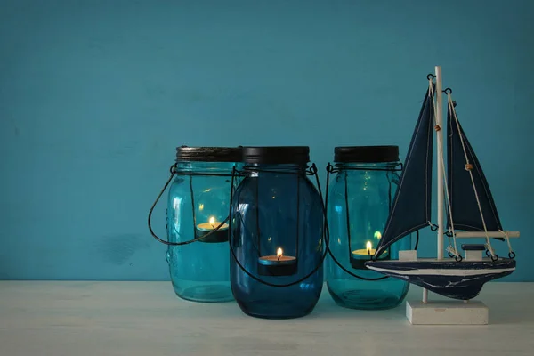 Tarros mágicos de albañil con luz de vela y barco de madera en el estante — Foto de Stock