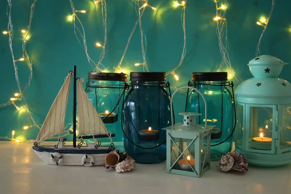 Magical mason jars whith candle light and wooden boat on the shelf. Nautical concept. — Stock Photo, Image