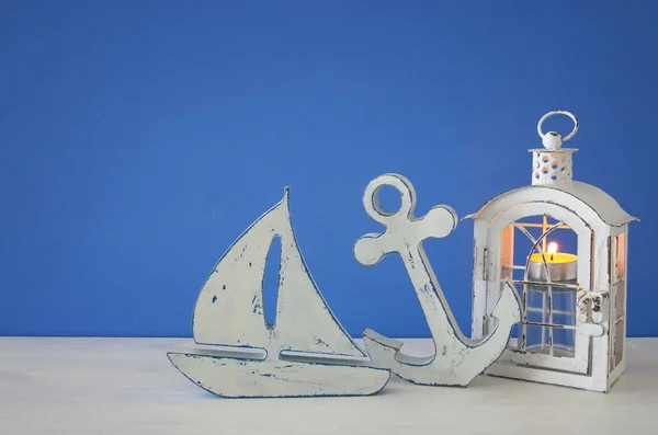 Linterna mágica con luz de vela y barco de madera en el estante. Concepto náutico — Foto de Stock