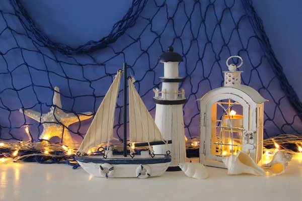 Linterna mágica con luz de vela y barco de madera en el estante. Concepto náutico —  Fotos de Stock