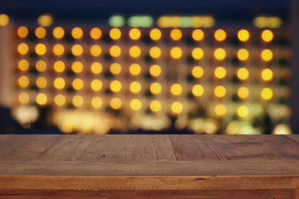 Ξύλινο τραπέζι μπροστά από το ξενοδοχείο bokeh νύχτα. Έτοιμο για προϊόν οθόνη μοντάζ — Φωτογραφία Αρχείου