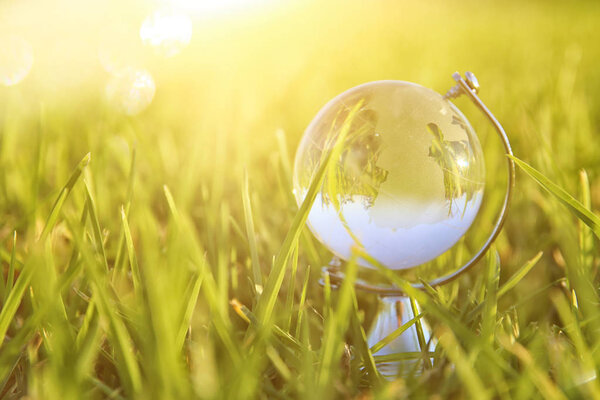 low angle of small crystal globe in the grass. travel and global concept