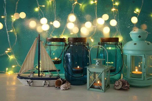 Magical mason jars whith candle light and wooden boat on the shelf. Nautical concept. — Stock Photo, Image