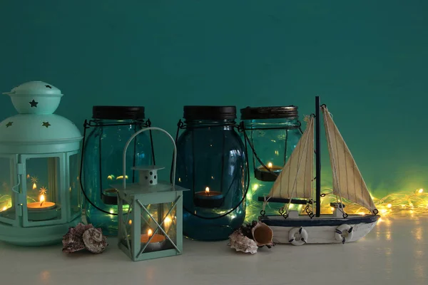 Frascos mágicos de albañil con luz de vela y barco de madera en el estante. Concepto náutico — Foto de Stock