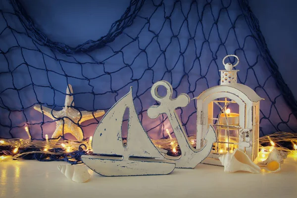 Lanterna mágica com luz de vela e barco de madeira na prateleira. Conceito náutico — Fotografia de Stock