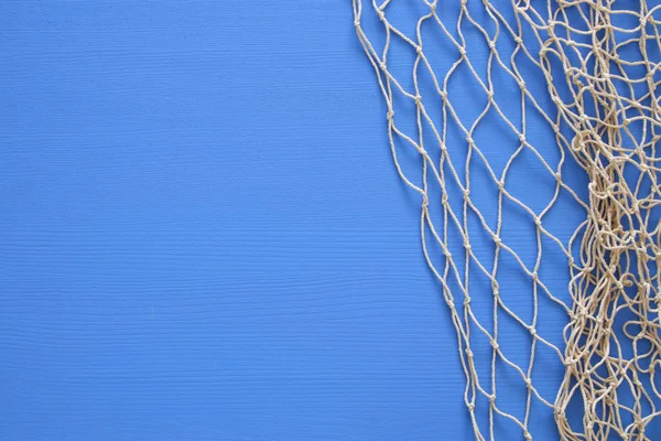 Vista superior de Fishnet em fundo de madeira azul — Fotografia de Stock