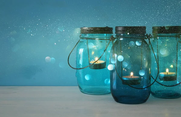 Vintage dekorativ magiska mason jars med levande ljus på träbord. Glitter överlägg — Stockfoto