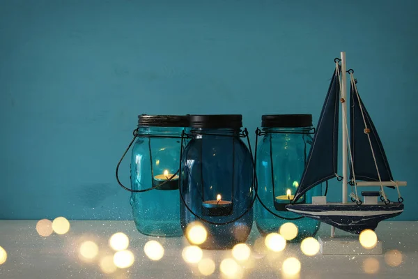 Magische mason jars whith kaars licht en houten boot op de plank — Stockfoto