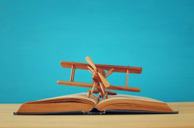 Oyuncak uçak ve ahşap masa üzerinde açık kitap.