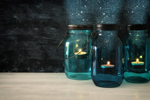 Tarros de albañil mágicos decorativos vintage con luz de vela en la mesa de madera — Foto de Stock