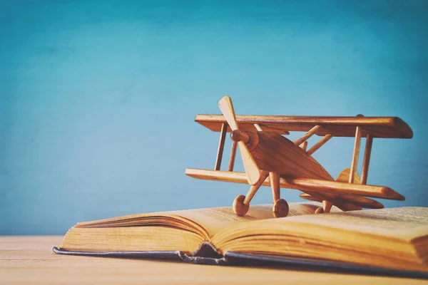 Spielzeugflugzeug und das aufgeschlagene Buch auf Holztisch — Stockfoto