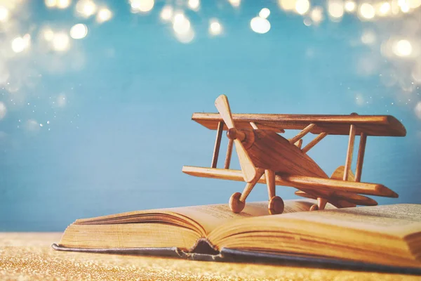 Oyuncak uçak ve ahşap masa üzerinde açık bir kitap. Glitter yerleşimi