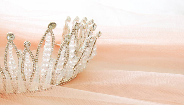 Vintage tulle pink chiffon dress and diamond tiara on wooden white table. Wedding and girl's party concept