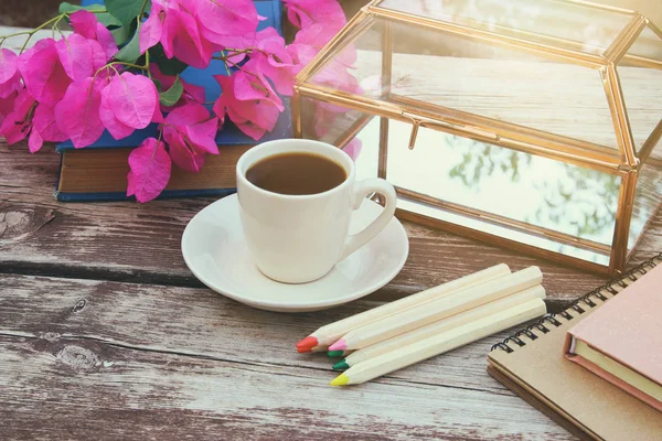Books, colorful pencils and cup of coffee on old wooden table outdoor in the park
