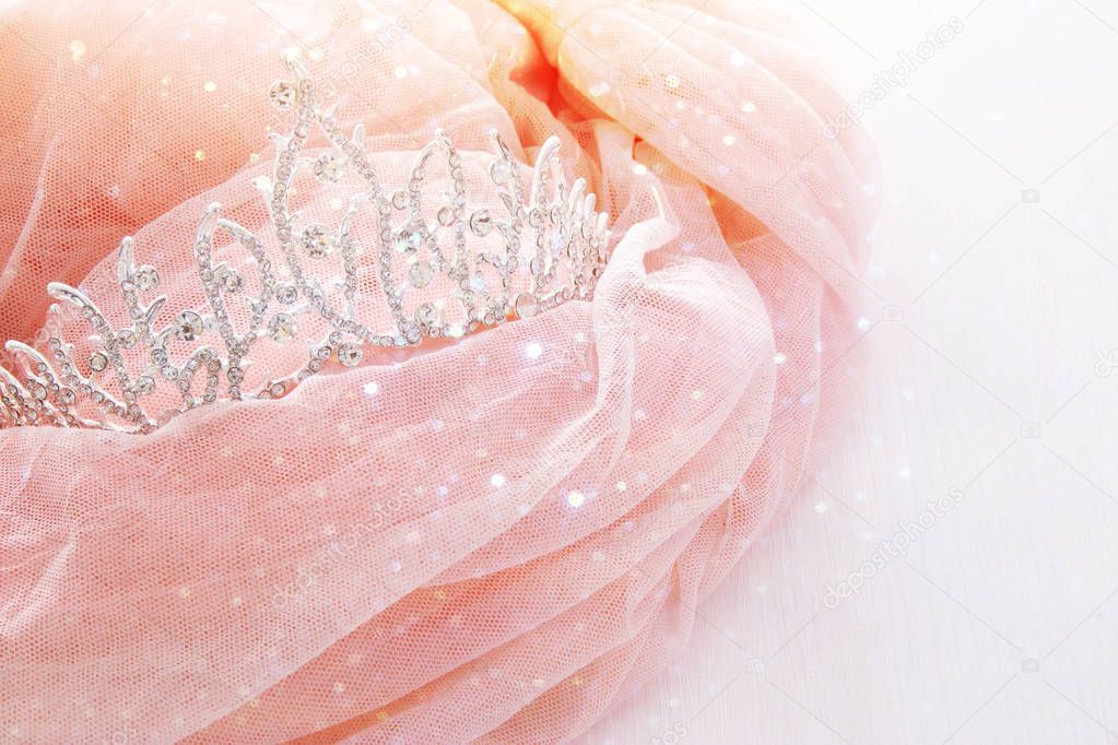 Vintage tulle pink chiffon dress and diamond tiara on wooden white table. Wedding and girl's party concept