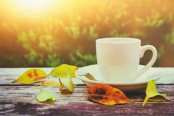 Tasse à café sur table en bois et feuilles d'automne devant le fond automnal — Photo